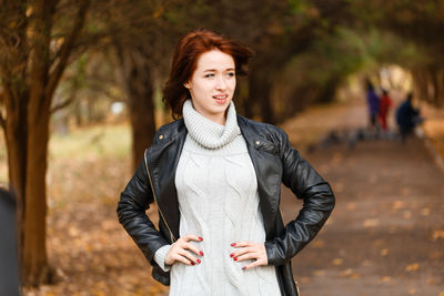Happy young woman relaxing in autumn nature. in gray sweater and leather