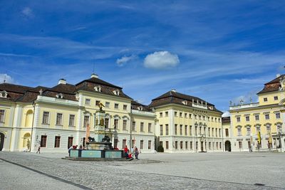 Buildings in town square against cloudy sky