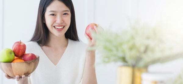 Portrait of a smiling young woman holding fruits