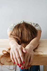 Redhead woman lying on table against wall