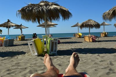 Low section of man lying on beach against clear sky