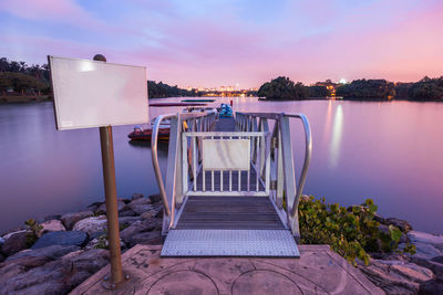 Pier over lake against sky during sunset