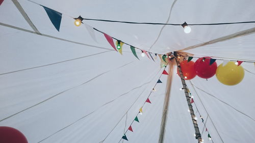 Low angle view of bunting and string light decoration against sky