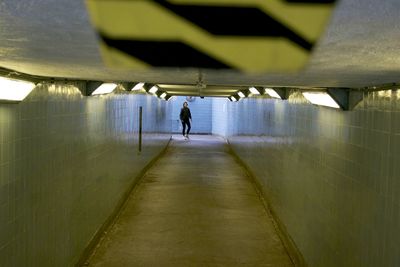Rear view of man walking in tunnel