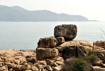 Rocks on shore by sea against sky