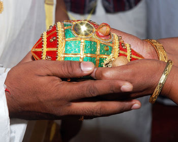 Cropped hands of couple holding shiny coconut during ceremony