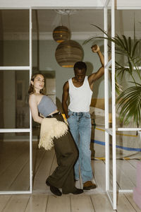 Portrait of fashionable woman leaning on doorway while posing with boyfriend at home