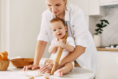 Mother kneading dough with son at home