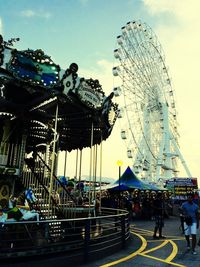 People in amusement park against sky in city