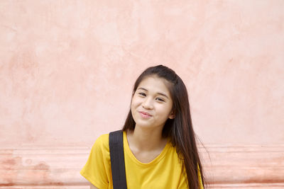 Portrait of smiling girl standing against wall