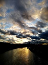 Scenic view of lake against dramatic sky during sunset