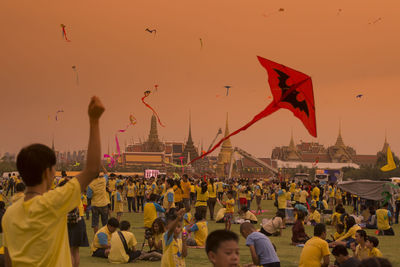 Crowd kite flying against sky during sunset in city during festival