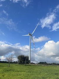 Windmills on field against sky