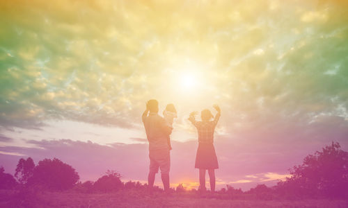 Rear view of women standing against sky during sunset