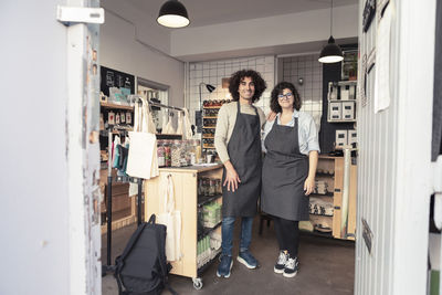 Full length of smiling male and female entrepreneurs standing in organic store