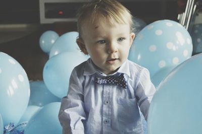 Baby boy amidst blue balloons during his birthday party