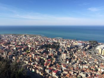 High angle view of townscape by sea against blue sky