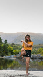 Full length of woman standing by lake against sky