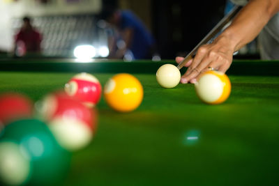 Cropped hand of man playing pool ball