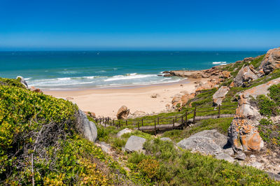 Summer beach nature background with wooden path to sandy beach and rocky coastline. south africa
