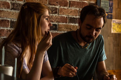 Young couple eating salad from paper containers while sitting in bar