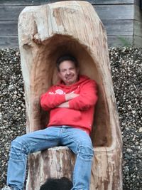 Portrait of a smiling young man sitting on wood