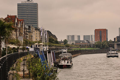 Bridge over river by buildings in city against sky