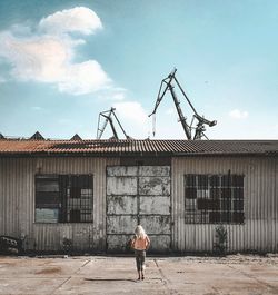 Woman standing by building against sky
