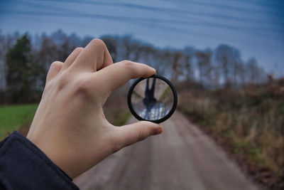 Cropped hand holding lens outdoors