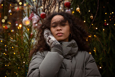 Portrait of woman standing by christmas tree