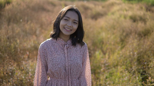 Portrait of a smiling young woman standing on field