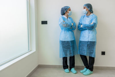 Nurses in surgery clothes standing with arms crossed in hospital