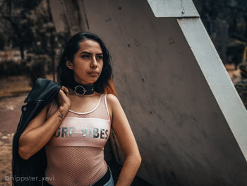 Portrait of young woman standing against wall