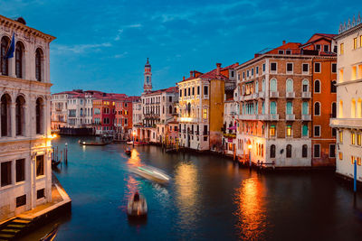 Venice's grand canal at sunset with illuminated historic buildings and light trails of tourist boats