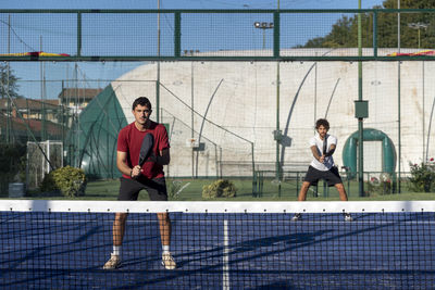 Man with friend playing paddle tennis at sports court