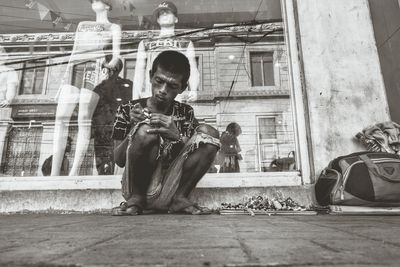 Full length of boy sitting in front of building