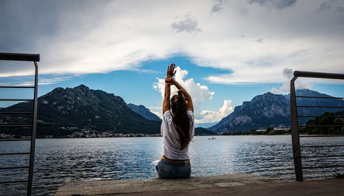 Rear view of woman standing by lake against mountain