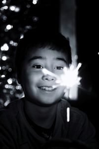 Boy looking at illuminated sparkler during night