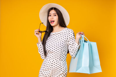 Young woman standing against yellow background