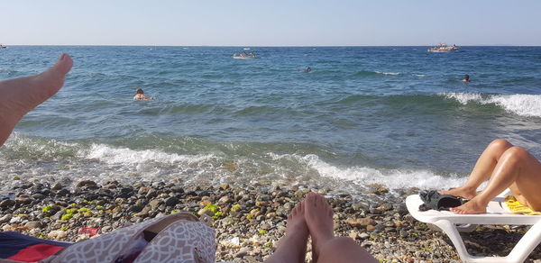 Low section of people on beach against sky