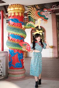 Portrait of woman in blue modern cheongsam holding a red fan at chinese temple 