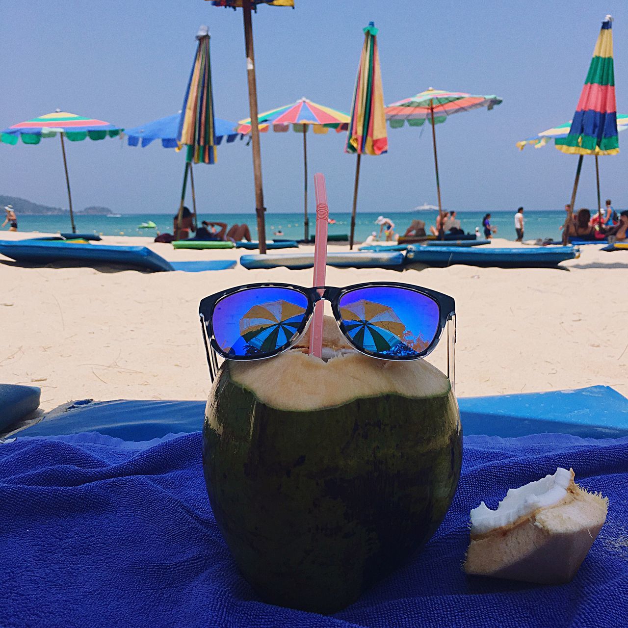 sea, beach, water, nautical vessel, sand, shore, moored, blue, sky, group of objects, boat, tranquility, transportation, tranquil scene, horizon over water, beach umbrella, sunlight, multi colored, day, nature