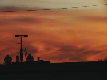 Silhouette of city against dramatic sky during sunset