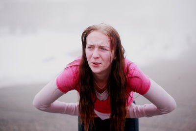 Young woman standing against wall