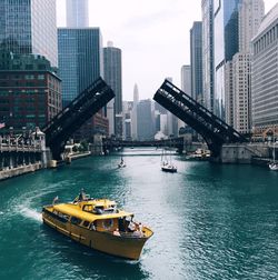 Boats and bridges over chicago river amidst modern buildings