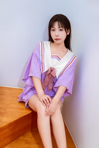 A smiling girl in a purple outfit poses on the stairs with a peace sign