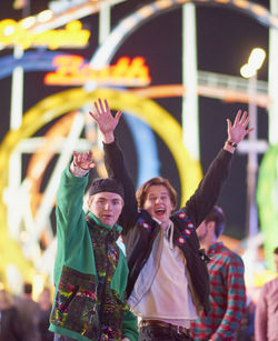 Friends enjoying at amusement park during night