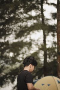 Rear view of boy on plant against trees