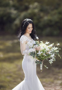 Smiling bride holding bouquet at park