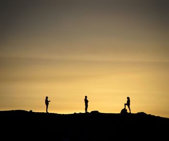 Silhouette people standing against sky during sunset